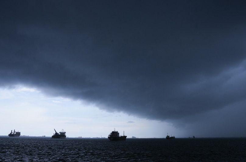 Storm clouds gather overhead as cargo ships that wait to move through the Panama Canal.