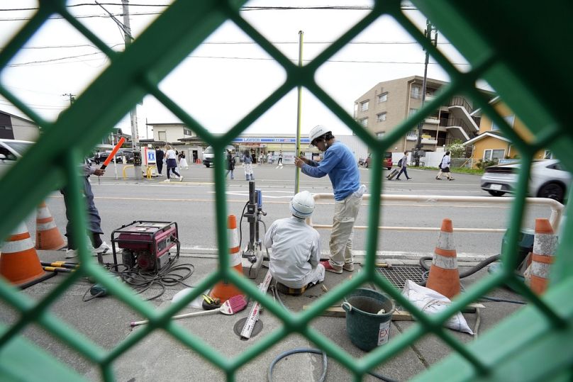 Workers set up a barricade near the Lawson convenience store with Mount Fuji in the background on Tuesday
