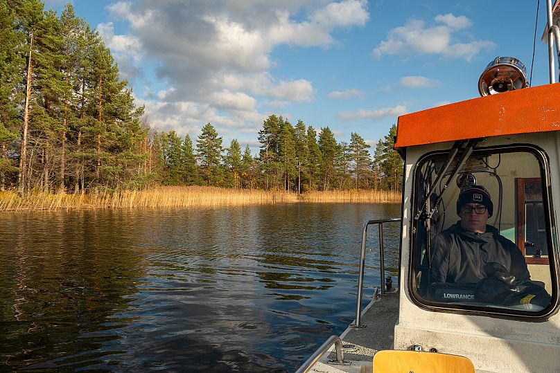 A fisherman drives a boat across Lake Puruvesi, Finland.