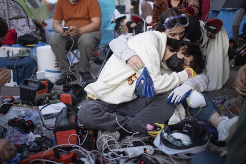 Pro-Palestinian demonstrators embrace while charging devices at an encampment on the UCLA campus Wednesday, May 1, 2024, in Los Angeles.