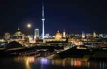 Der Mond geht am Montag, 22. November 2021, über der beleuchteten Skyline der deutschen Hauptstadt in Berlin, Deutschland, auf.