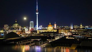 La lune se lève au-dessus de la ligne d'horizon illuminée de la capitale allemande à Berlin, en Allemagne, le lundi 22 novembre 2021.