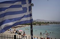 People enjoy the sea as a Greek flag waves at Alimos beach,