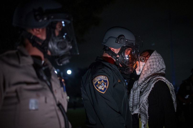 Filistin atkısı takan Filistin yanlısı bir öğrenci, UCLA kampüsünde polisle tartışırken