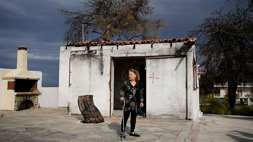 Retiree Chrysoula Renieri, 73, stands outside her house which was burned in July 2023 during a wildfire, in Loutraki, Greece, 25 April 2024.
