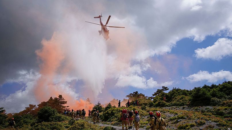 A helicopter drops water during a drill, as firefighters in training for the special unit, practice near Villia village 60 kilometres northwest of Athens, 19 April 2024.