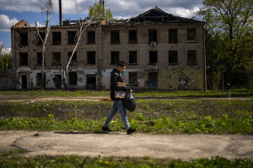 A young man walks past to partially destroyed building in Russian attacks in Borodyanka, north of Kyiv, April 2024