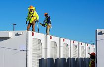  Des travailleurs vérifient les modules de stockage des batteries d'une installation de stockage d'énergie solaire au lithium-ion en Arizona, aux États-Unis.