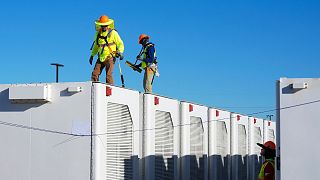  I lavoratori controllano le capsule di accumulo delle batterie in un impianto solare di accumulo di energia con batterie agli ioni di litio in Arizona, negli Stati Uniti.