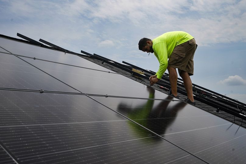 ARCHIVO - Nicholas Hartnett, propietario de Pure Power Solar, fija un panel solar en el tejado de una casa en Frankfort, Kentucky, el lunes 17 de julio de 2023.