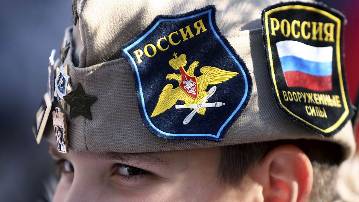 A boy wears Russian insignia on his hat, 12 March 2022