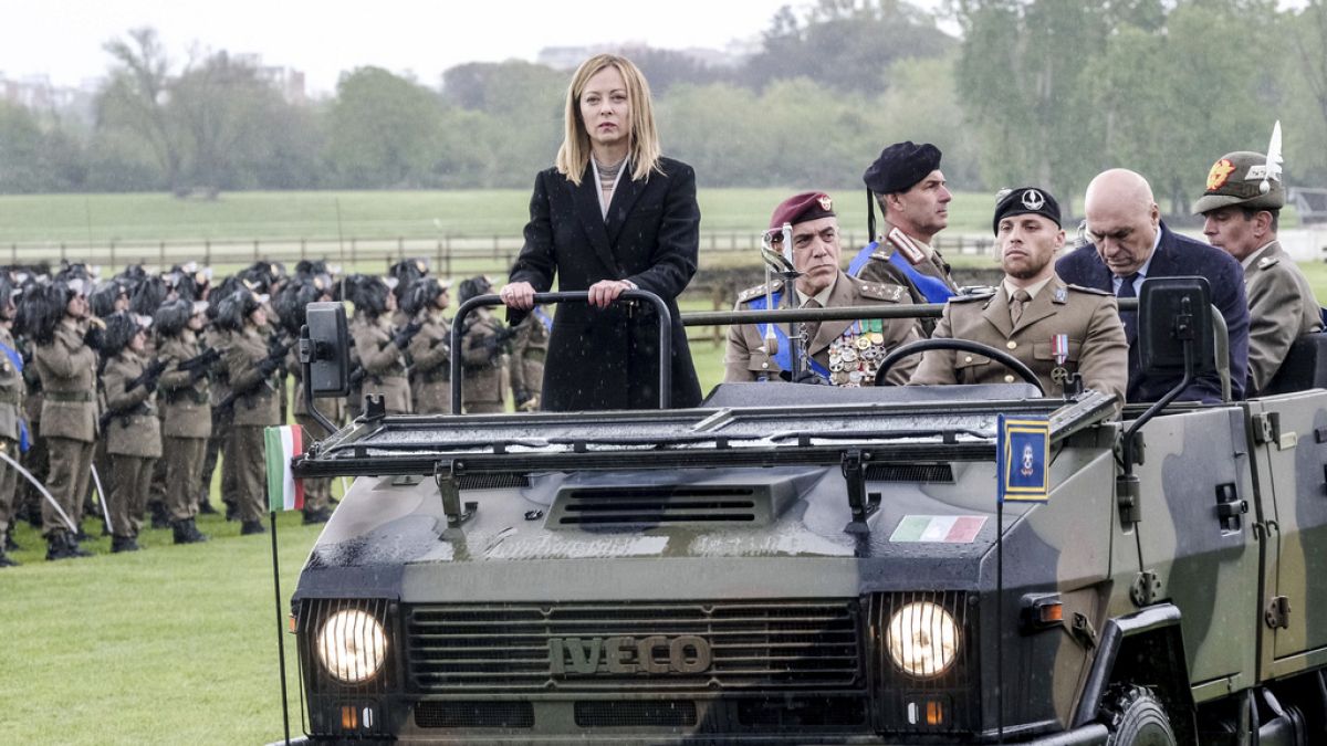 Italian Premier Giorgia Meloni stands on a military jeep flanked by the Italian Army Chief of Staff Carmine Masiello, Friday, May 3, 2024.