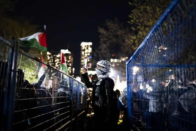 Bir protestocu, Toronto Üniversitesi kampüsünde kurulan Filistin yanlısı kampın çevresindeki destekçileri görüntülüyor