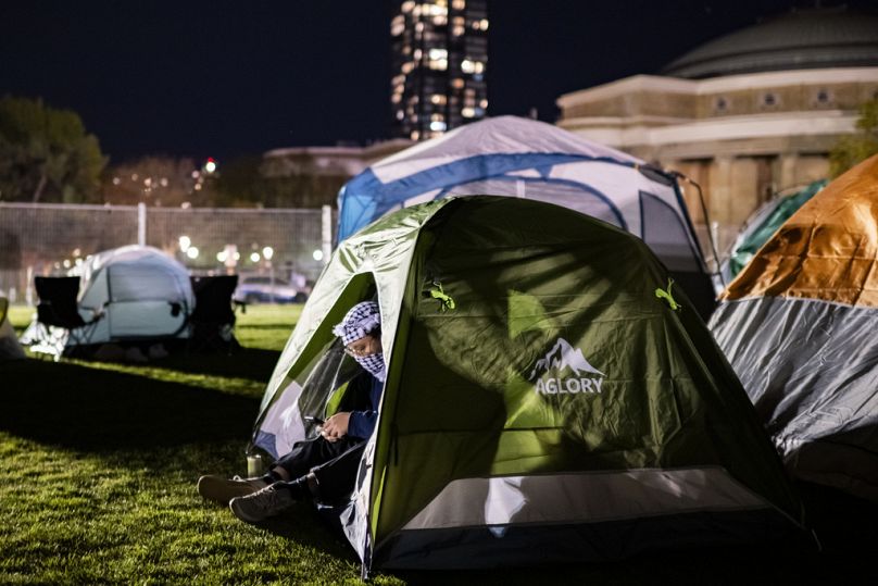 Kanada'daki Toronto Üniversitesi kampüsünde kurulan Filistin yanlısı kampta bir protestocu çadırında oturuyor