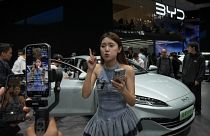 Modell beszél egy BYD autó előtt a kínai autóshow-n