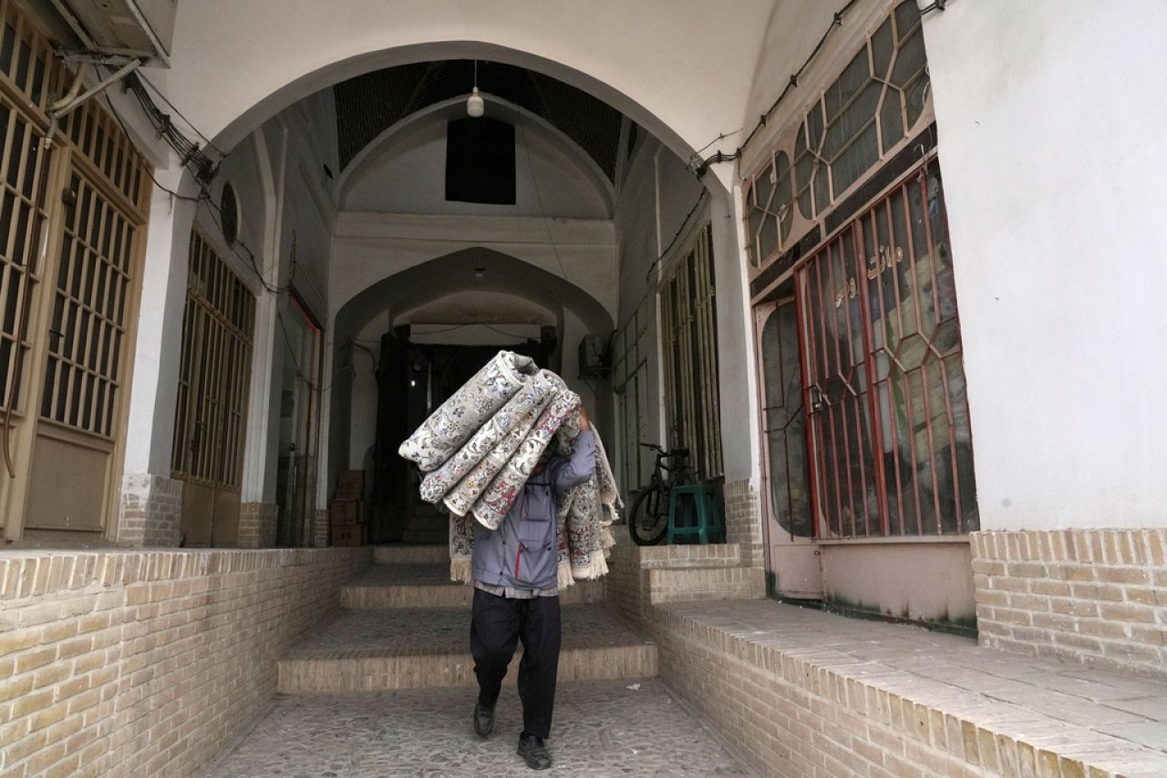 A worker carries carpets at the traditional bazaar of the city of Kashan, about 152 miles (245 km) south of the capital Tehran, Iran, Tuesday, April 30, 2024.