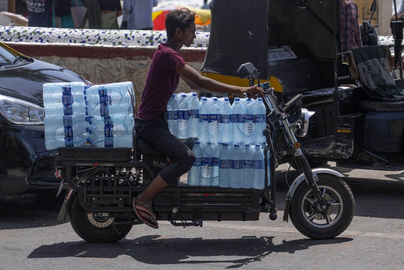 A man transports packaged drinking water on his bike on a hot summer day in Mumbai, India.