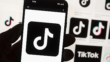 The TikTok logo is displayed on a mobile phone in front of a computer screen, 14 October 2022. 
