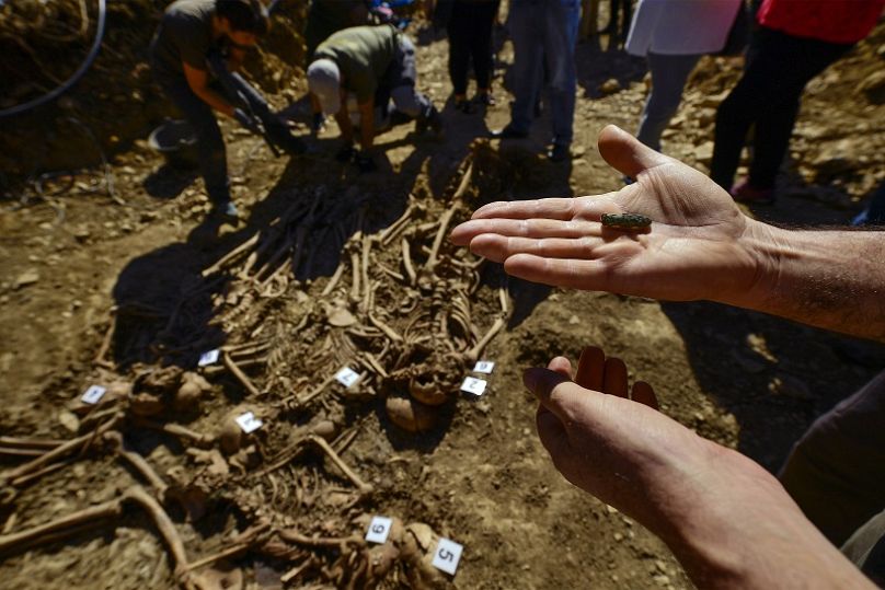 Un arqueólogo muestra una bala utilizada para la ejecución, mientras inspeccionan una tumba en el pequeño pueblo de Ollacarizqueta