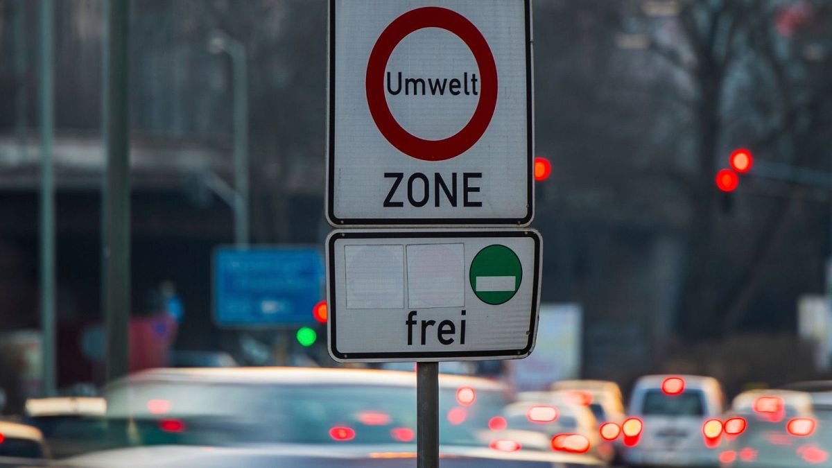Cars pass by a sign reading 'environment zone' and allowing entrance just for cars with low emissions in Germany.