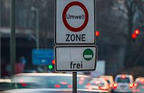 Os carros passam por uma placa onde se lê 'zona ambiente' e permitindo a entrada apenas para carros com baixas emissões na Alemanha.