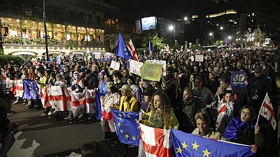 Manifestantes con banderas nacionales georgianas y de la UE marchan durante una protesta