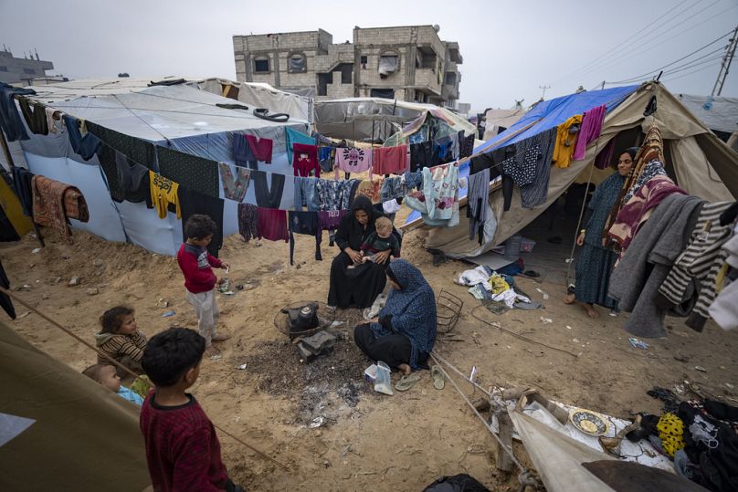 Palestinians displaced by the Israeli bombardment of the Gaza Strip make tea at the makeshift tent camp in the Muwasi area on Thursday, Dec. 28, 2023.