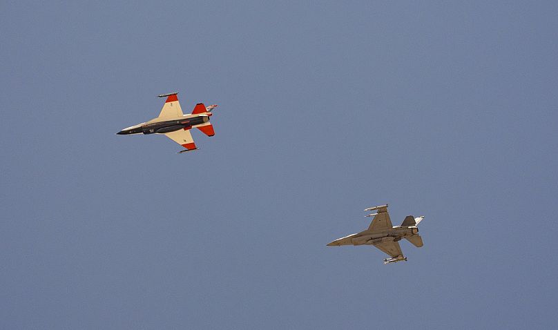 Un avión de combate F-16 de la Fuerza Aérea con IA, a la izquierda, vuela junto a un F-16 adversario, mientras ambos aviones vuelan a 304 metros de distancia entre ellos.