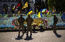 Ukrainian service men stand next to Ukrainian flags and photographs placed in memory of civilians and soldiers killed during the war in Kyiv. April 20, 2024 
