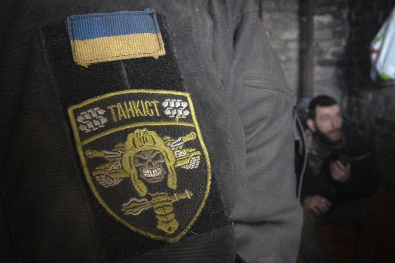 Un soldat de la 17e brigade blindée ukrainienne se tient dans un abri, un chevron indiquant « Tankiste » sur sa manche. 29 février 2024