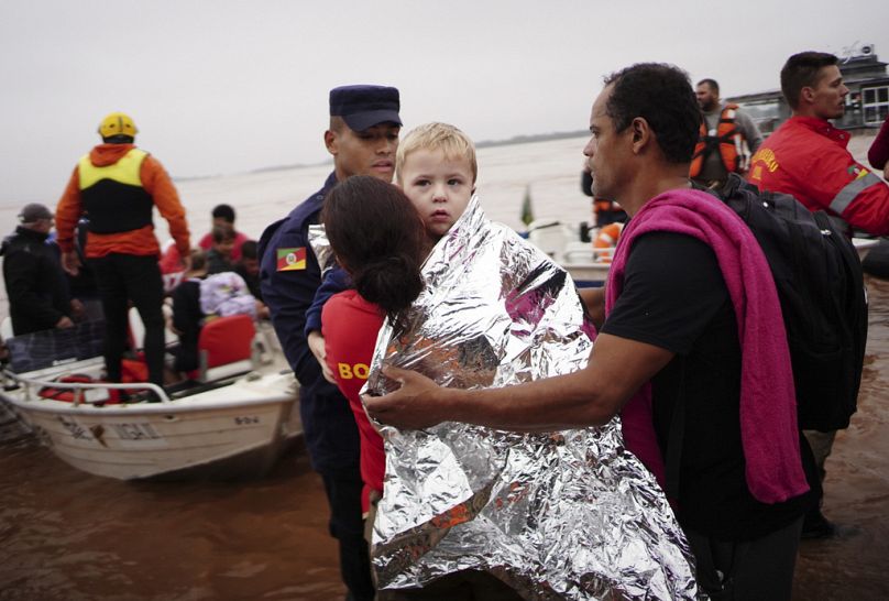 A member of the Civil Defense carries a child rescued from an area flooded by heavy rains in Porto Alegre, Rio Grande do Sul state, Brazil, Saturday, May 4, 2024.