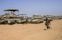 An Israeli soldier walks past a line of tanks at a staging ground near the border with Gaza in southern Israel, May 5, 2024
