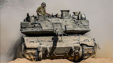 Israeli soldiers drive a tank at a staging ground near the border with the Gaza Strip, 5 May 2024