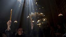 Una peregrina cristiana sostiene velas mientras la gente se reúne durante la ceremonia del Fuego Sagrado en la Iglesia del Santo Sepulcro, en Jerusalén.