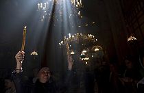Una peregrina cristiana sostiene velas mientras la gente se reúne durante la ceremonia del Fuego Sagrado en la Iglesia del Santo Sepulcro, en Jerusalén.