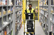 A worker collects goods for purchase orders at a storehouse of the Amazon Logistic Center in Germany.