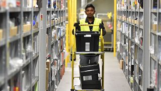 A worker collects goods for purchase orders at a storehouse of the Amazon Logistic Center in Germany.