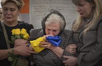 Мать погибшего украинского военного целует флаг Украины во время похоронной процессии в Киеве 6 мая