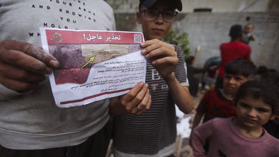 Palestinians hold leaflets dropped by Israeli planes calling on them to evacuate ahead of an Israeli military operation in Rafah, southern Gaza Strip, Monday, May 6, 2024. 