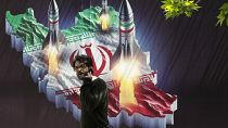 Ένας άνδρας περπατά μπροστά από ένα πανό που δείχνει πυραύλους να εκτοξεύονται από έναν ιρανικό χάρτη στην Τεχεράνη, 19 Απριλίου 2024