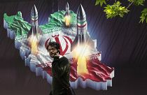 A man walks past a banner showing missiles being launched from an Iranian map in Tehran, April 19, 2024