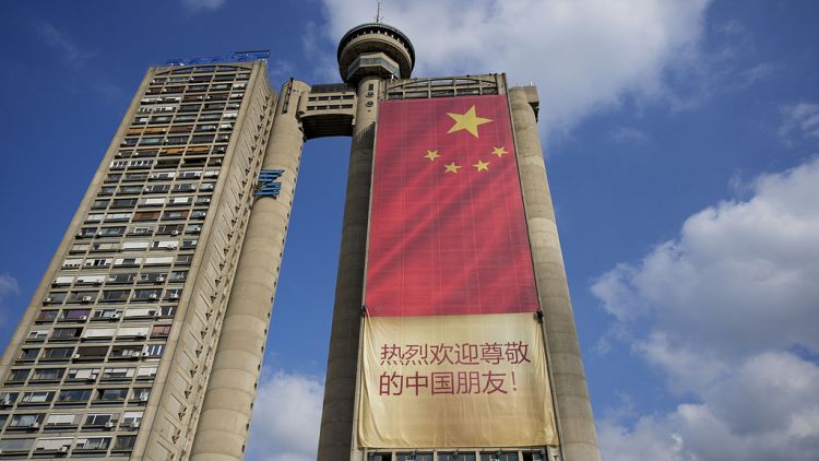 Workers hang on ropes to install a giant Chinese national flag on a skyscraper that is a symbolic gateway leading into the city from the airport, in Belgrade, Serbia