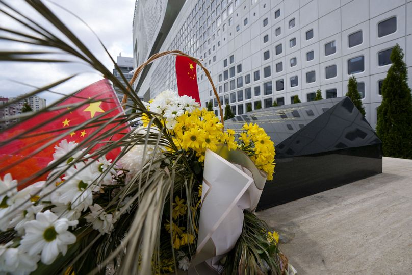 Un drapeau chinois est placé près de fleurs sur un monument sur le site de l'ancienne ambassade de Chine à Belgrade, en Serbie, le samedi 4 mai 2024.