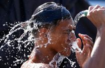 A man pours water from a pipe over himself on a hot day in Manila, Philippines.