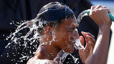 Um homem despeja água de um cano sobre si próprio num dia quente em Manila, nas Filipinas.