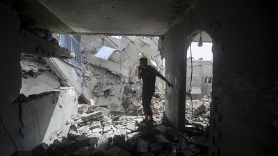 Palestinianos observam a destruição após um ataque israelita a um edifício residencial em Rafah, 7 de maio de 2024