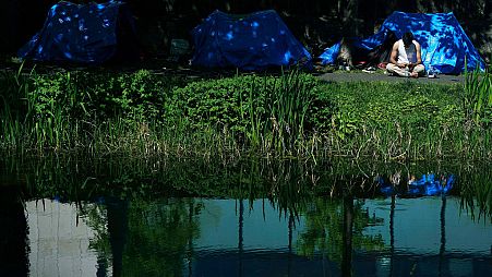 A man sits outside one of the dozens of tents which have been pitched by migrants along a stretch of the Grand Canal, in Dublin, Sunday May 5, 2024.