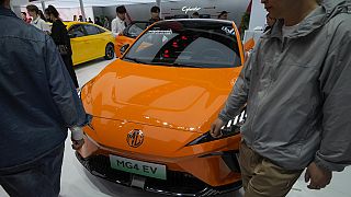Visitors walk by a MG4 EV car on display during the Auto China 2024 in Beijing