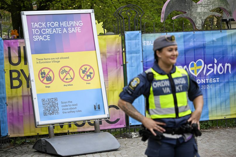 Uma segurança em frente a um painel informativo na Aldeia da Eurovisão no parque Folkets, em Malmo, Suécia