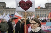 Um manifestante segura um cartaz com a inscrição "Democracia" em frente ao Reichstag durante uma manifestação contra o partido AfD e o extremismo de direita em Berlim, fevereiro de 2024